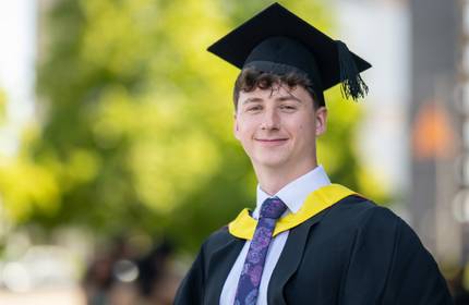 A young man wearing a graduation cap and gown.