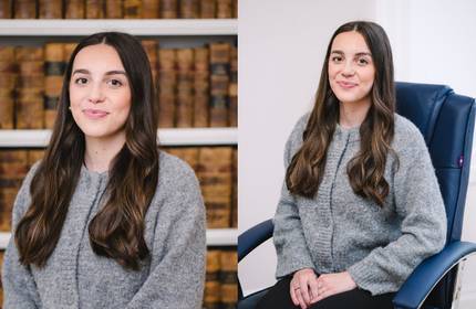 A young woman stands in front of shelves of law books.