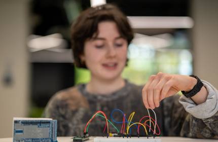 A person adjusts wires connected to a circuit board.