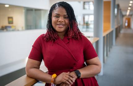 A young woman leans against the railing of a balcony in the Cardiff School of Management Atrium.