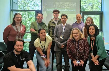 A small group of people pose for a photograph in a meeting room