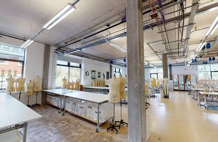 Rows of tables in a large room, with tailor's dummies and sewing machines