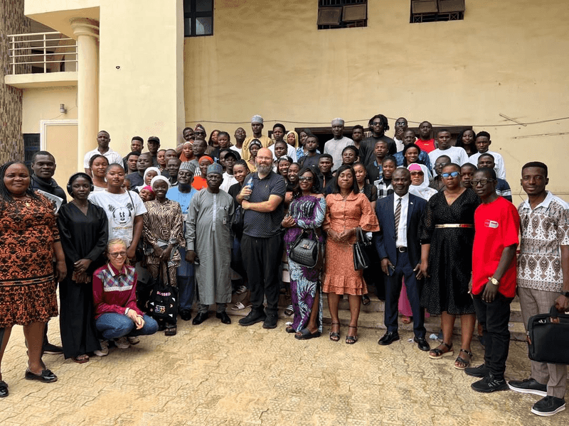 A large group of adults stand in a semi circle for a photograph