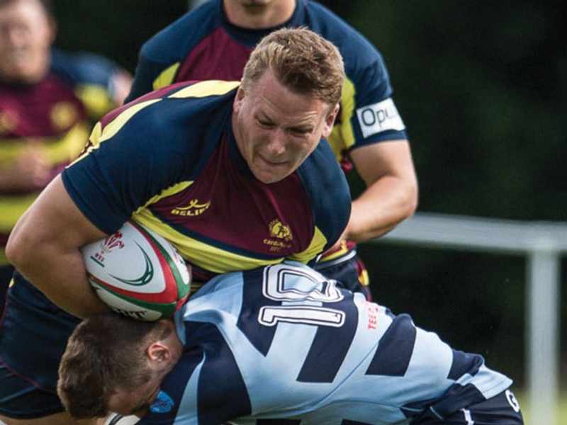 Alex Dombrandt gets tackled around the waist during a game of rugby