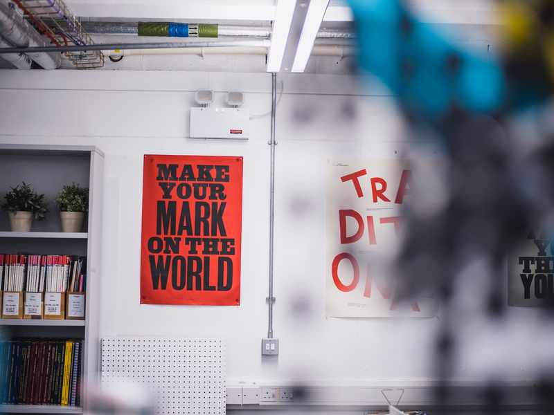 Two artistic posters displayed on a white workshop wall
