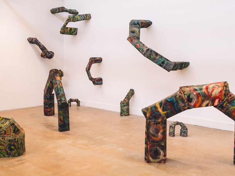 A series of abstract metal art pieces fill an open art space and walls