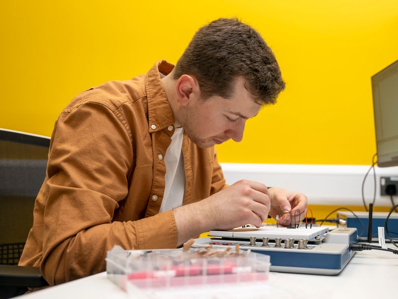 CST student works on a small circuit board at their desk
