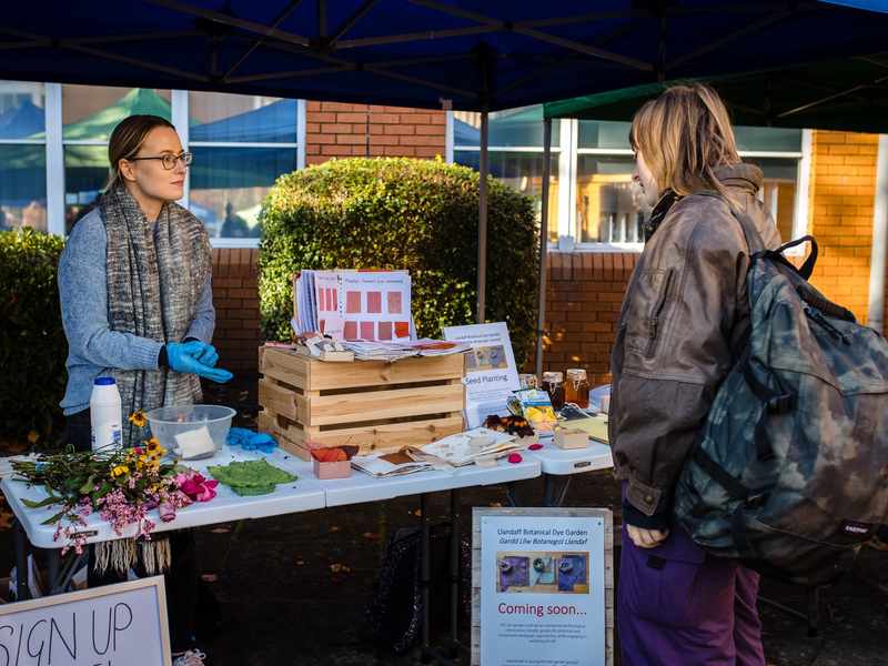 A young woman stands at a Sustainability information stand during a Community Event on Llandaff Campus