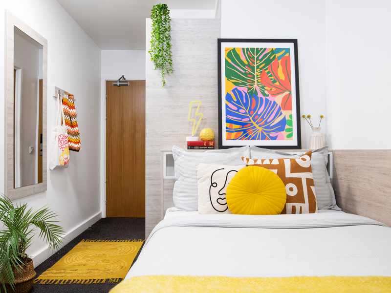 A colourful bedroom with bright bedding and striking artwork on the walls