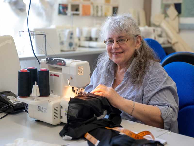 An elderly woman works at a sewing machine