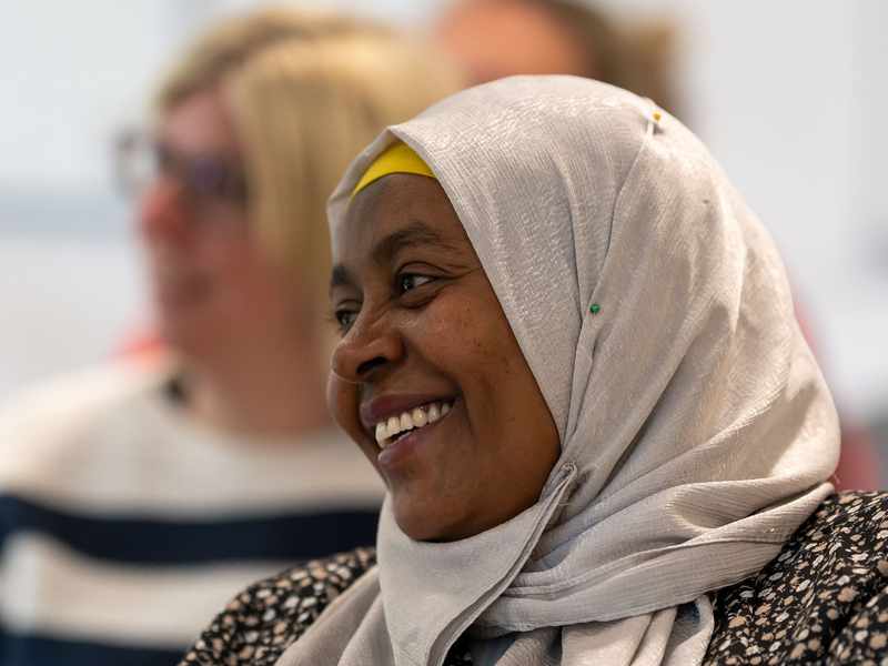 Adult woman in a white silver headscarf smiles