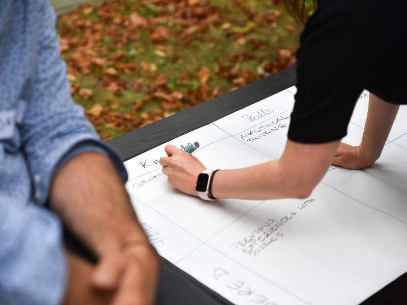 A close-up of a person writing on a large sheet of paper with a marker pen.