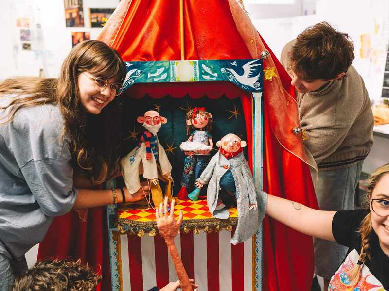 A group of students holding small hand puppets.