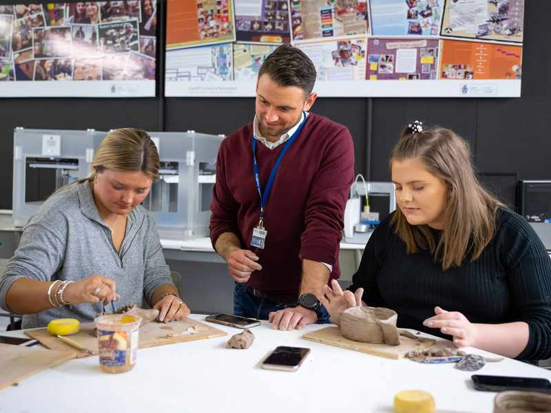 Lecturer with student teachers working with clay
