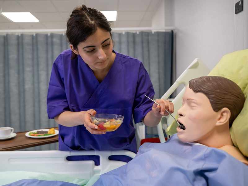 Nursing student feeding manikin