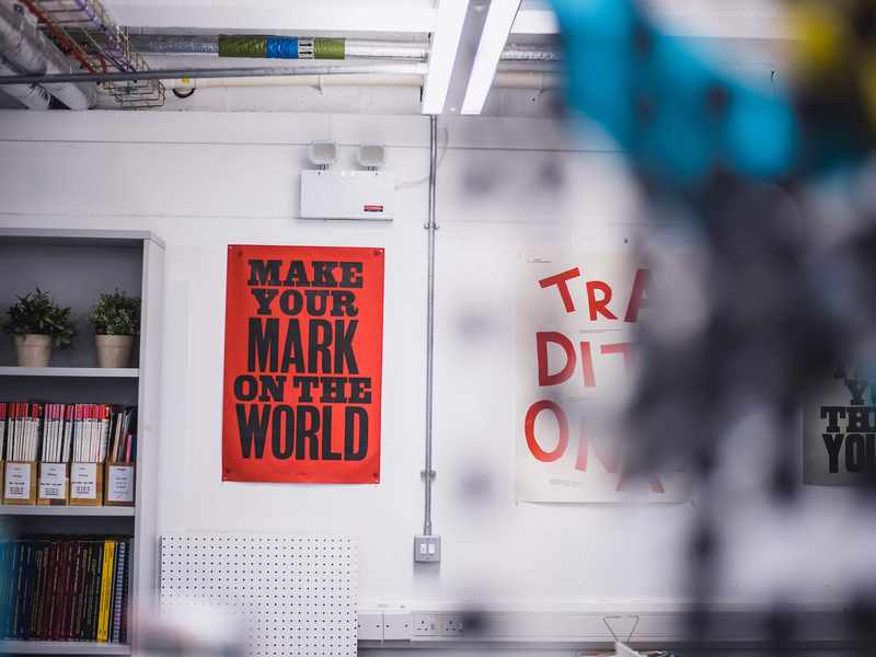 Two artistic posters displayed on a white workshop wall