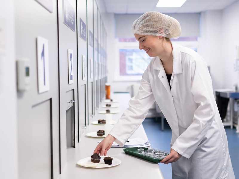 Student places cakes out for testing in Food Industry Centre evaluation suite