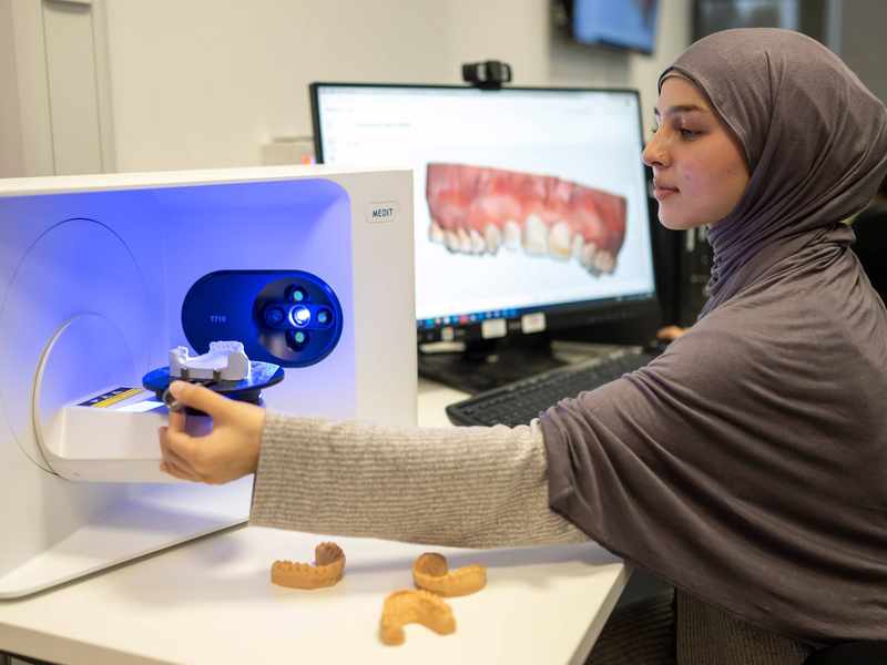 Student placing dental cast into 3d scanner