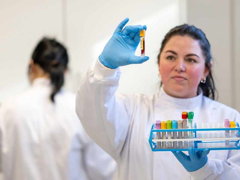 Student in laboratory coat holding test tube