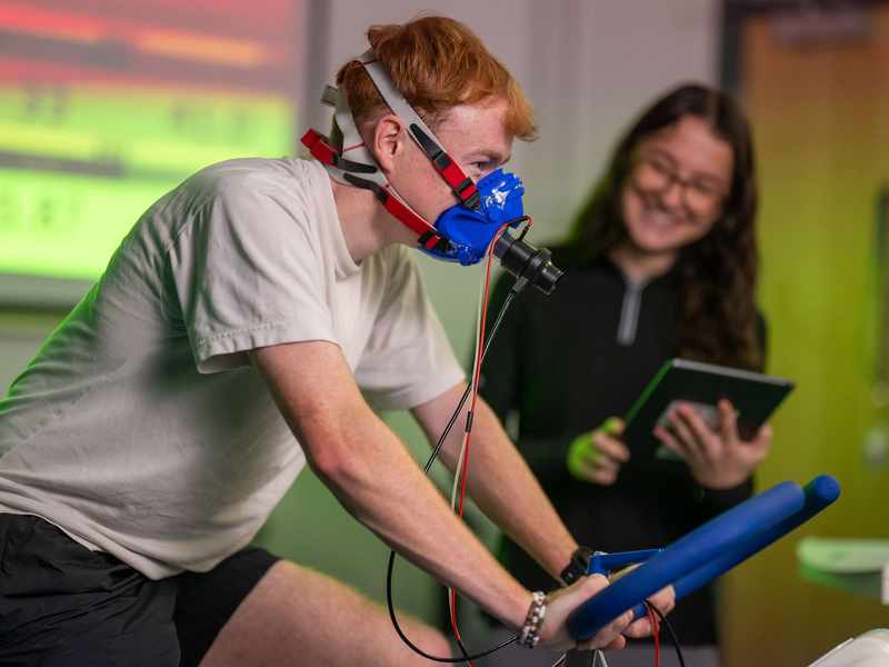 Student wearing oxygen mask on exercise bike