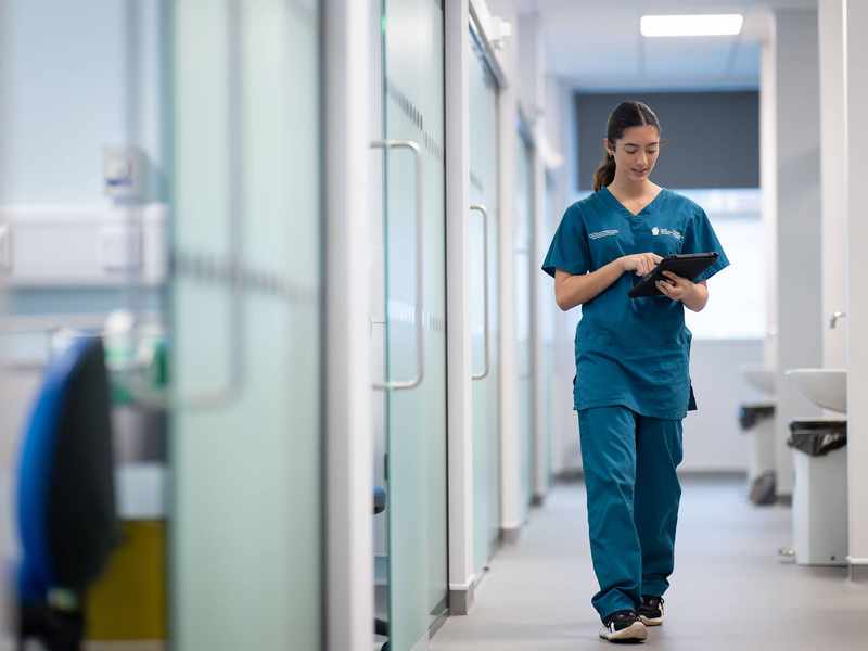Student holding tablet while walking through Allied Clinical Health Hub