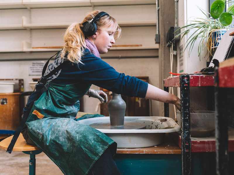A student makes a vase using a pottery wheel.