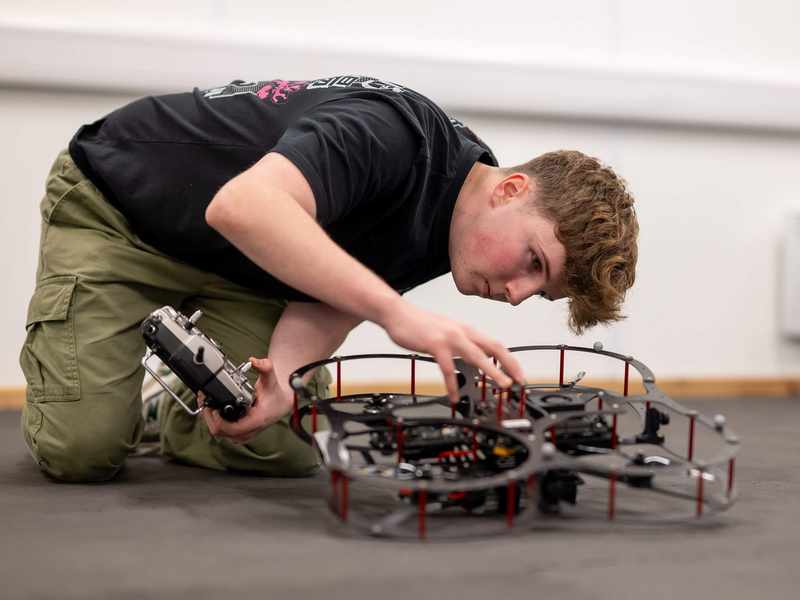 A student works with a small drone quadcopter.