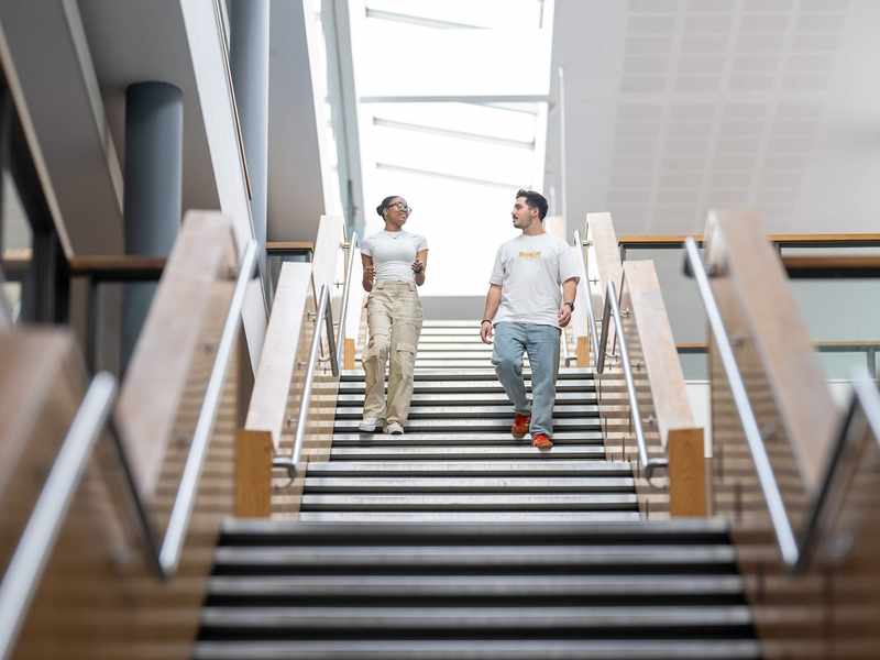 Two people walking down a staircase in a large, open space.