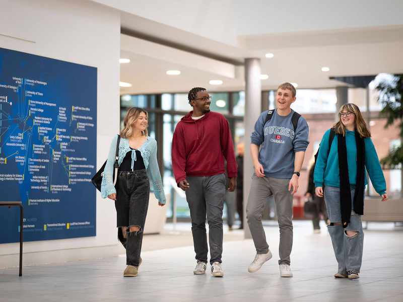 Four students walking alongside each other in the Cardiff School of Management.