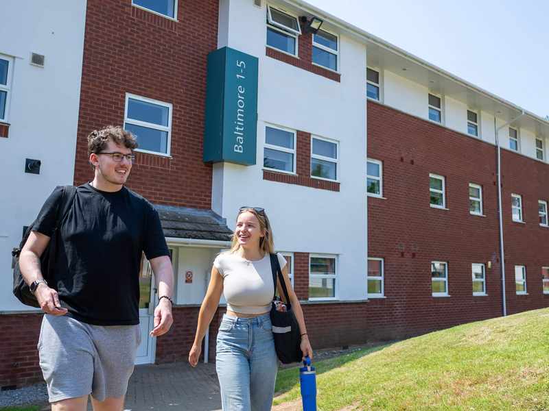 Two people walking together outside an accommodation block at Cardiff Met.