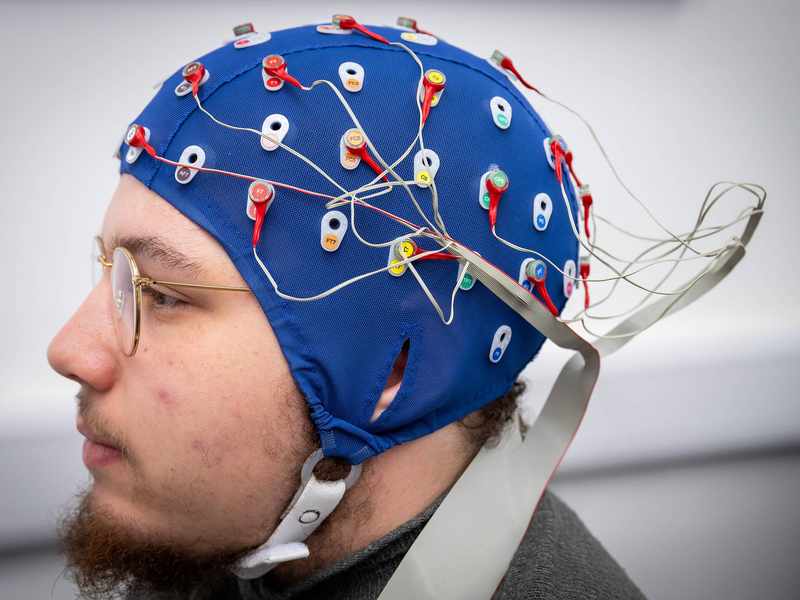 A close-up of a person wearing a cap fitted with electrical sensors.