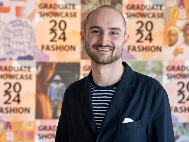 A person stands in front of a collage of posters.