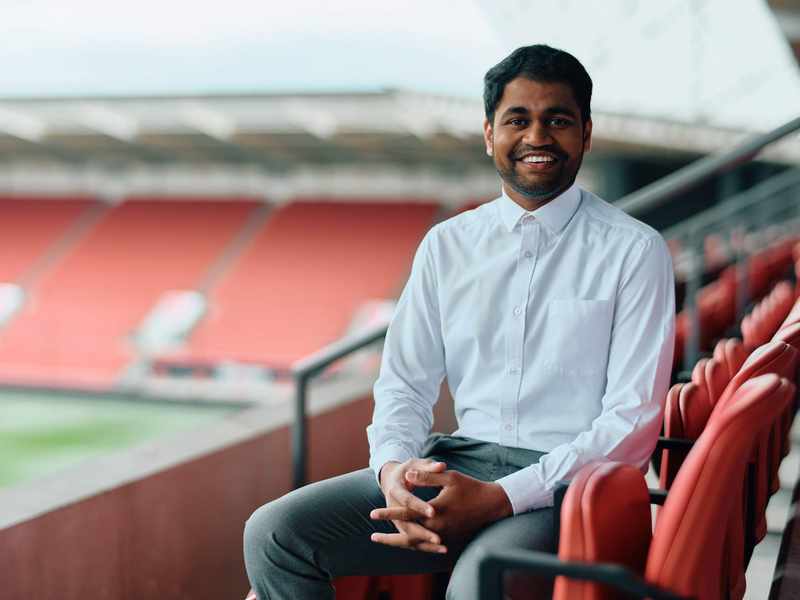 A person sits in the empty stands of a football stadium.