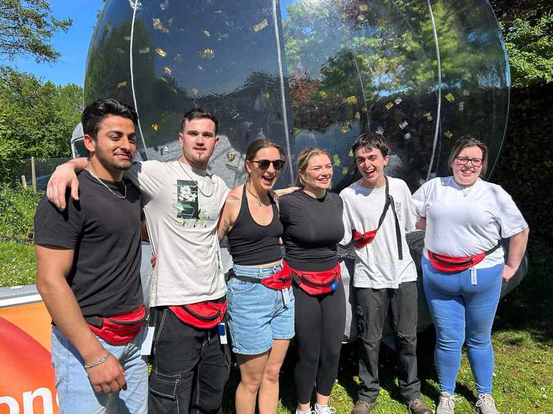 A group of people stand in a row, arm in arm.