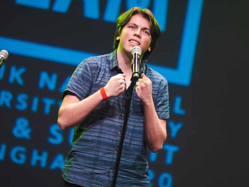 A person stands in front of a microphone on a stage.