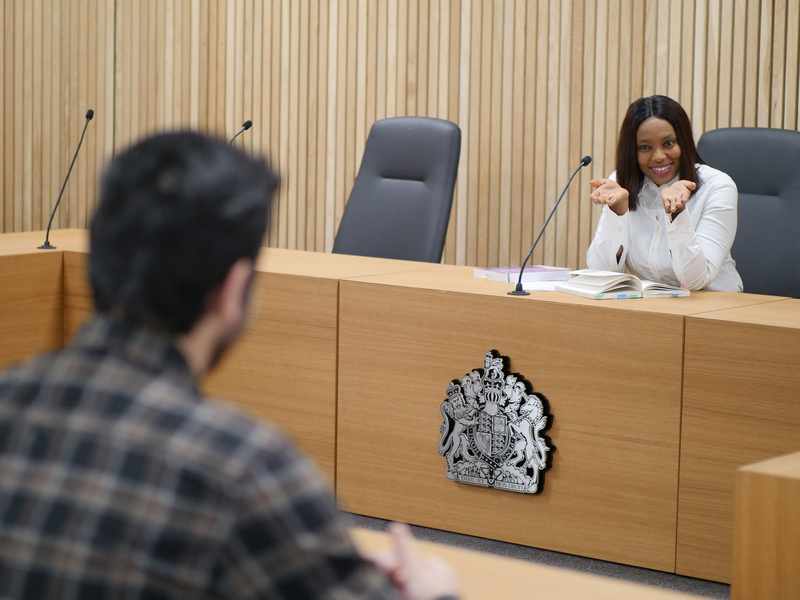 A person sits facing a courtroom bench.