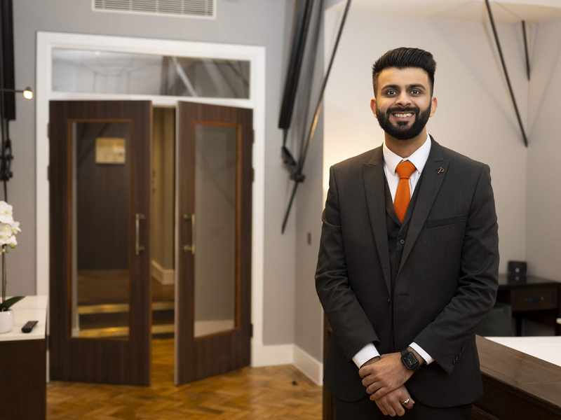 A person stands in the foyer of a stylish hotel.