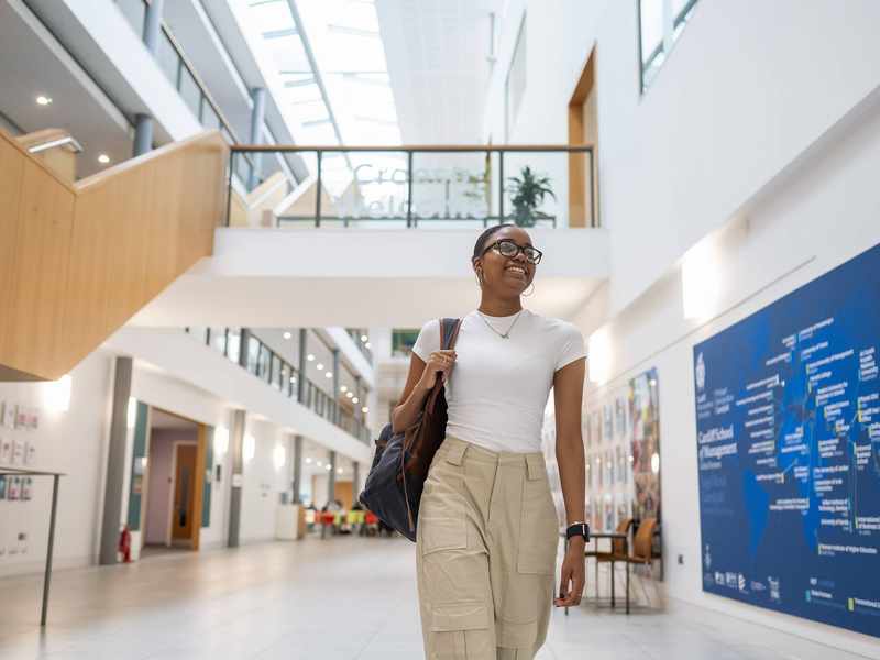 A student walks through the bottom floor of the Cardiff School of Management