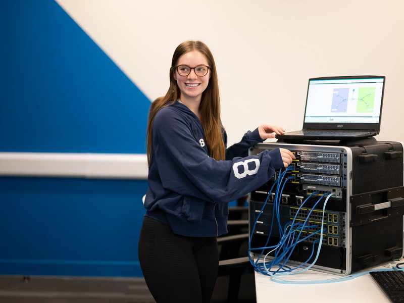 A person plugs cables into computer network equipment.