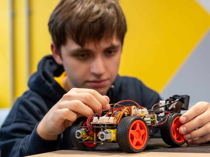A person assembling a wheeled robot.