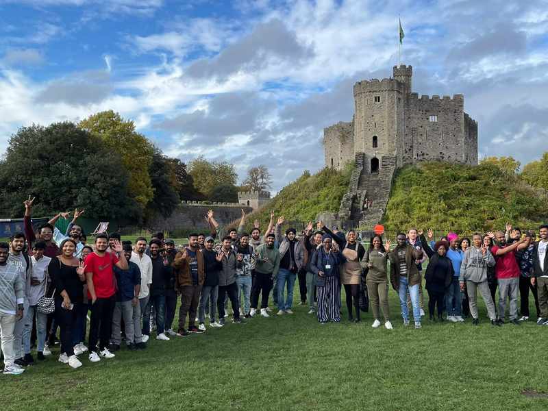 A large group of people line up in front of a castle-like structure.