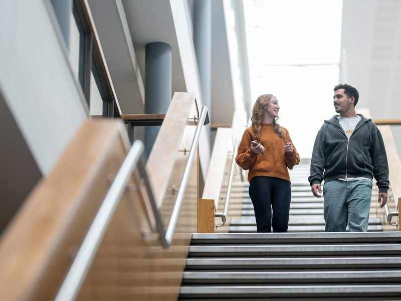 Two people walking down a staircase in a large, open space.