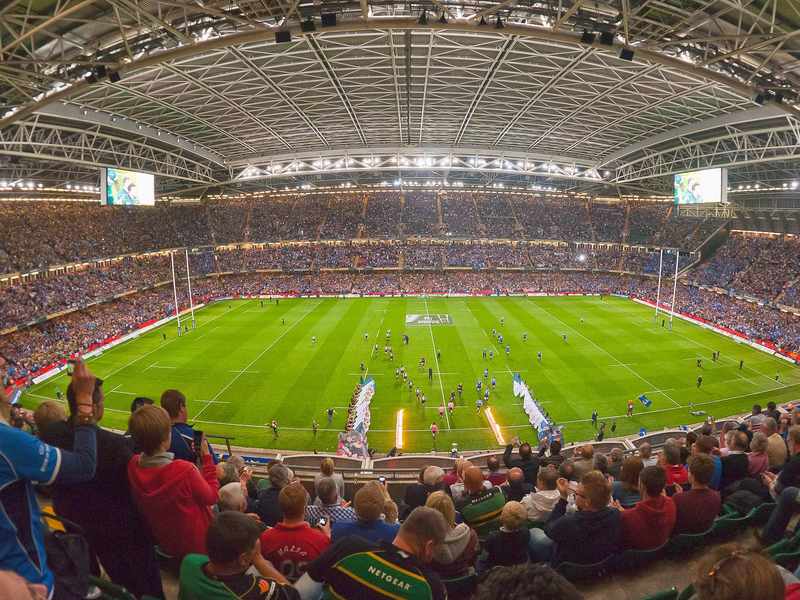 A large stadium filled with spectators watching a rugby match in progress.