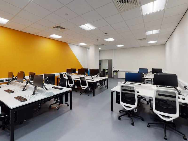 Clusters of work desks with office chair and computer screens in office room.