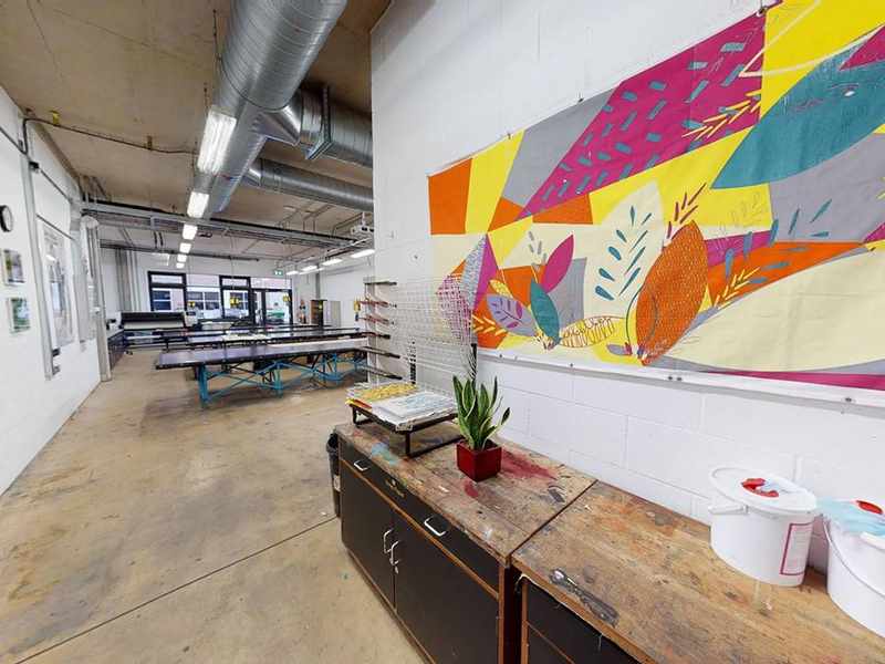 A sideboard beneath a brightly coloured fabric print mounted on a wall