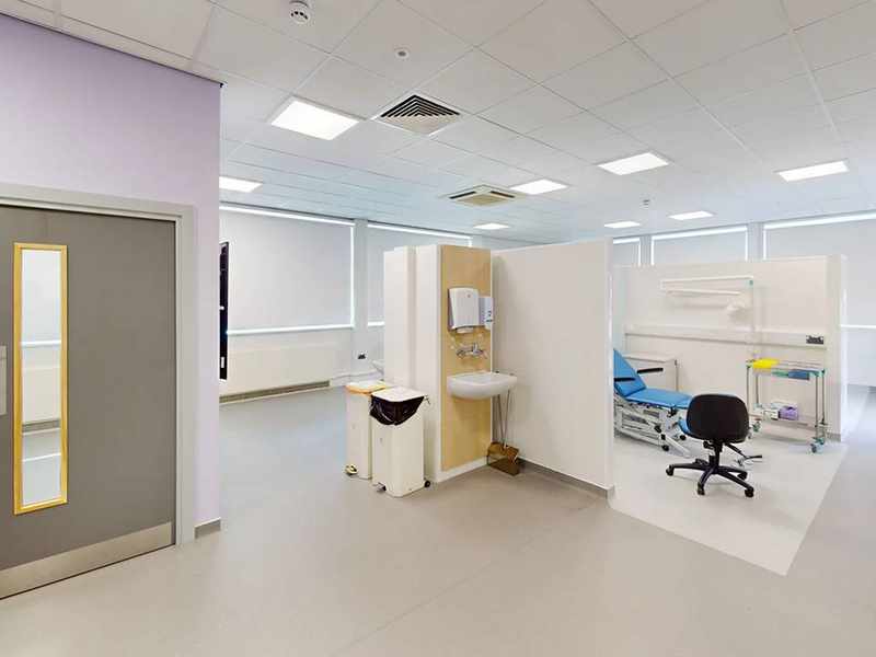 A large white room. In the centre is a partially-walled area with an examination chair.