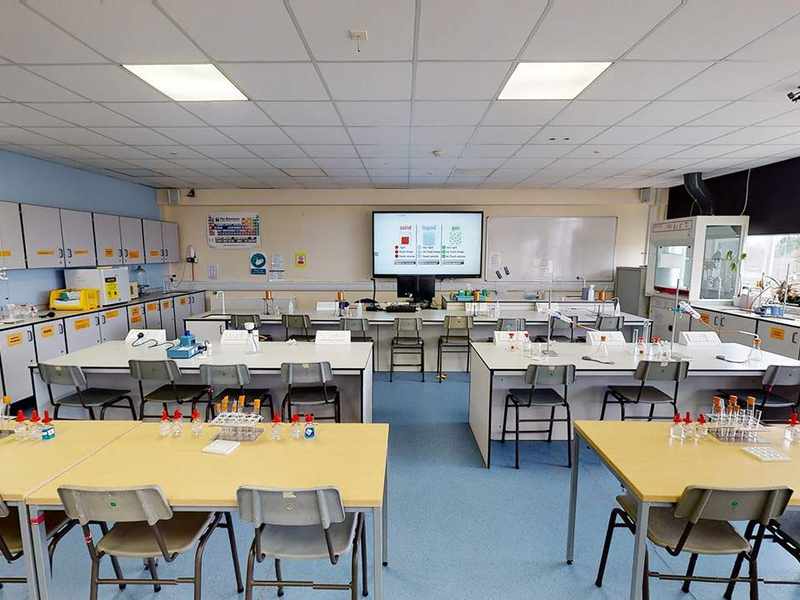 A large room with three rows of desks. On the desks are test tubes and beakers.