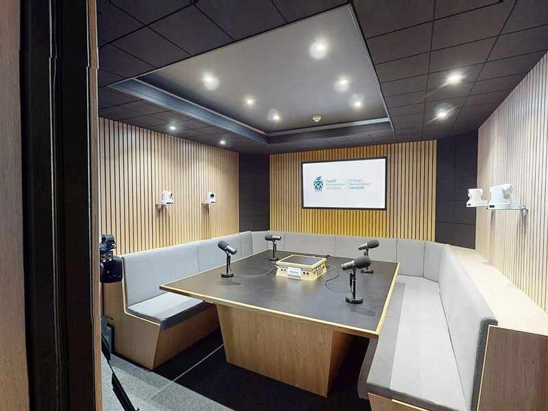 A podcast recording studio with curved seating, microphones and video cameras.