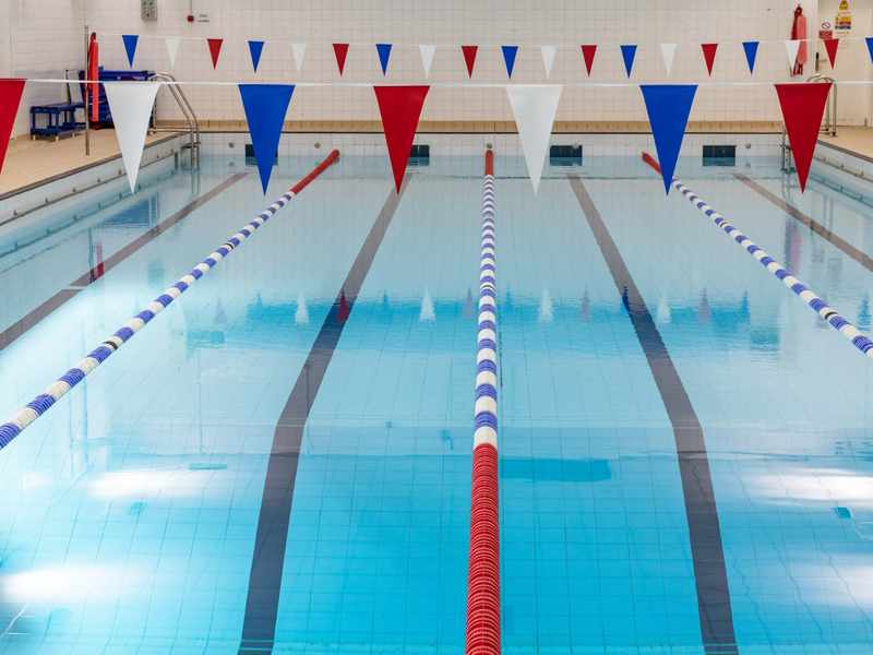 A swimming pool with race lanes and decorative bunting overhead