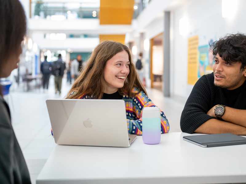 Three students engage in discussion inside the Cardiff School of Management